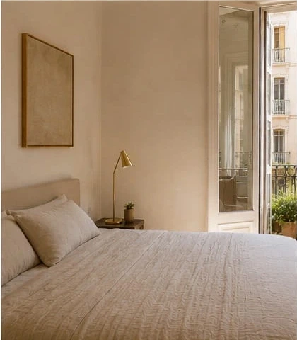 Serene Mediterranean bedroom with linen bedding and a brass reading lamp beside a balcony